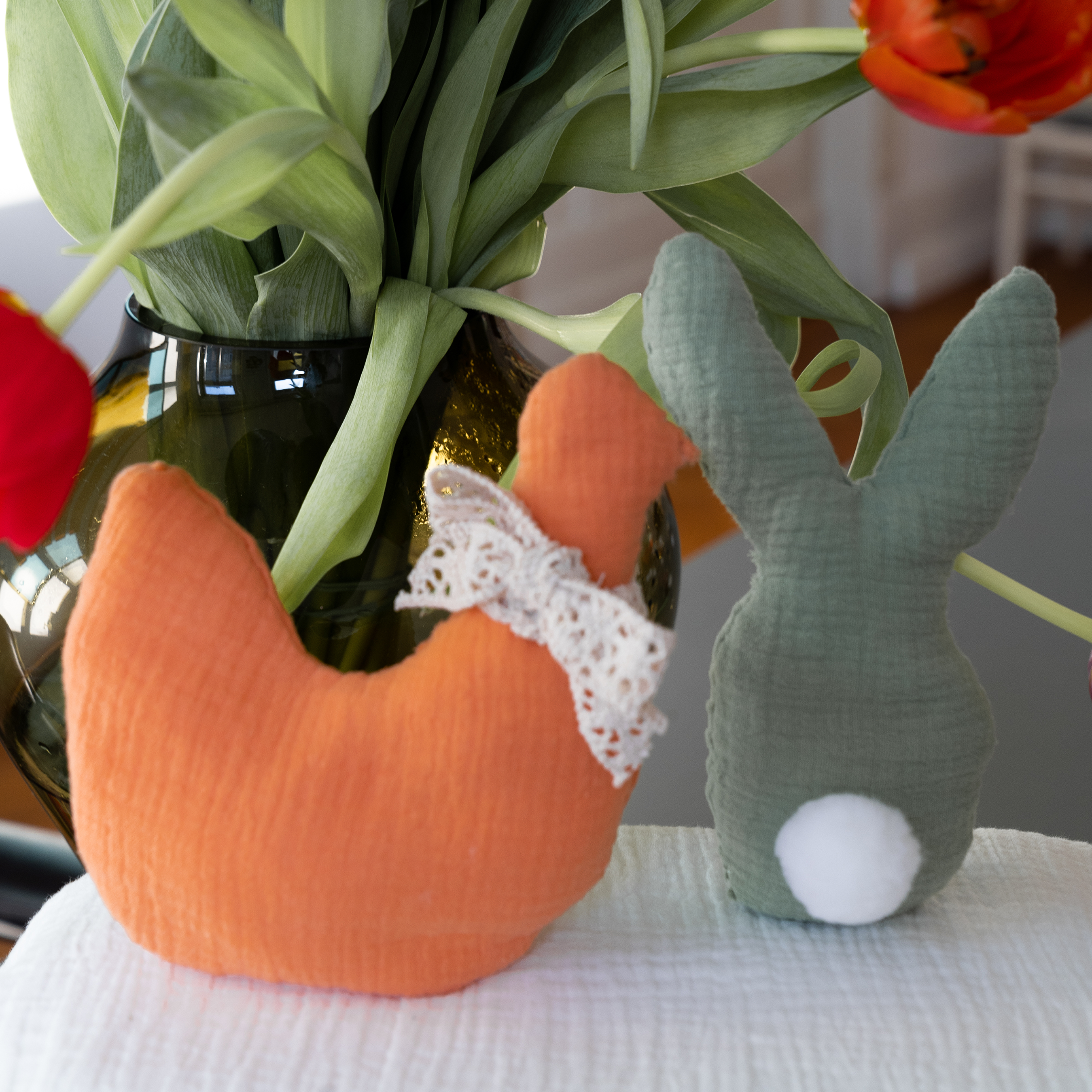 Stoffküken und Stoffhase vor einem Strauß Tulpen