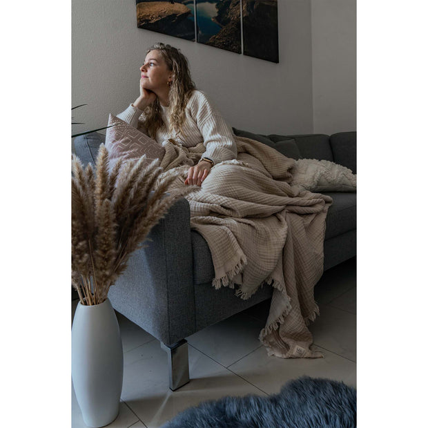 Musselin Plaid Sofadecke in der Farbe Beige Frau auf Couch 01