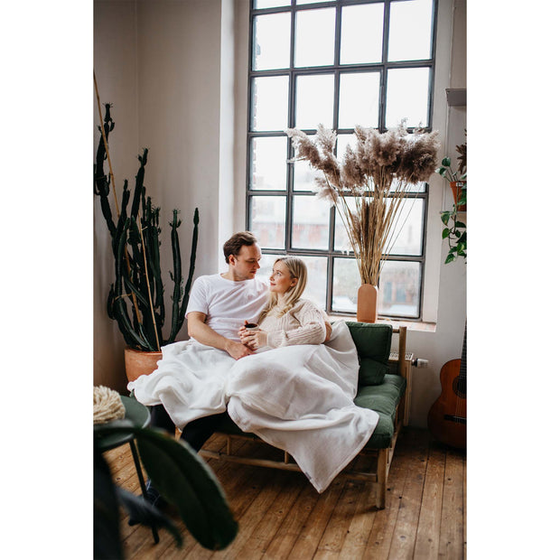 Musselin-Sofadecke Off-White Tragebild Paar liegt auf dem Sofa
